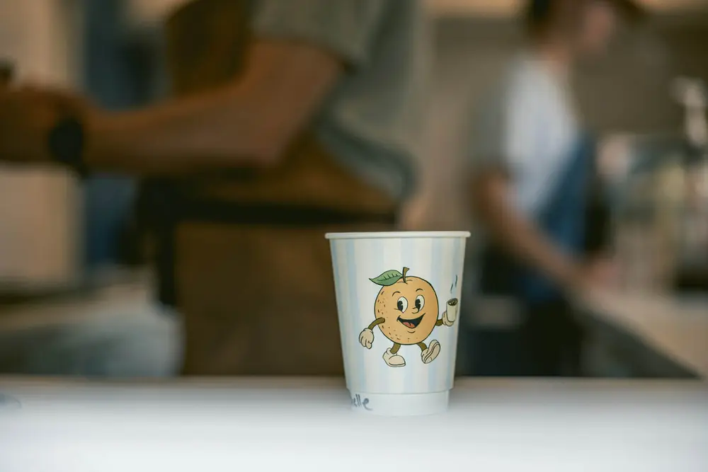 Striped Good Fruit cup with the walking orange mascot on the counter