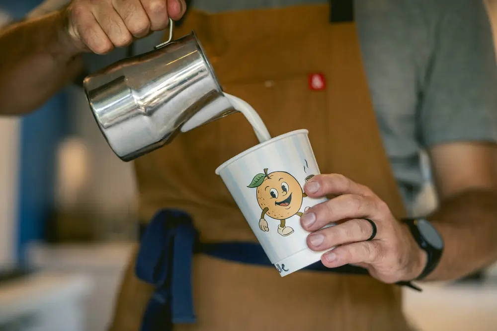 Barista pouring steamed milk into a striped Good Fruit cup