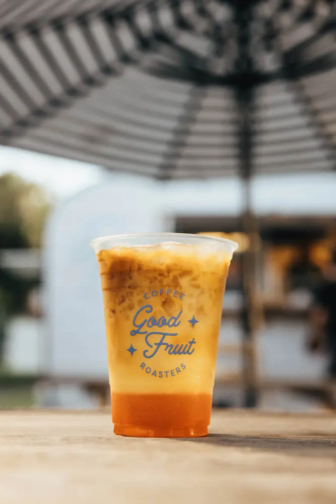 Iced Good Fruit latte on a picnic table under the striped umbrella